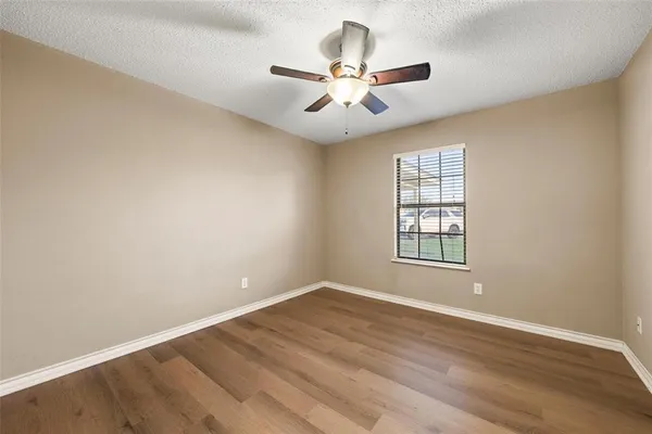 an empty room with wooden floor fan and windows
