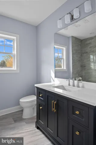a bathroom with a granite countertop toilet sink and mirror