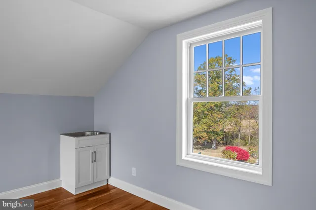 a view of an empty room with window and wooden floor
