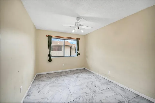 an empty room with windows and ceiling fan