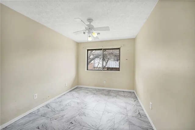 an empty room with a window and a fan