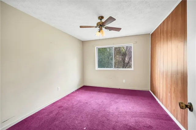 an empty room with a ceiling fan and windows