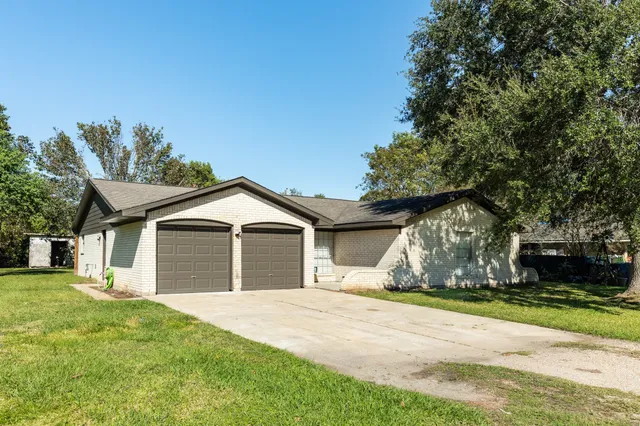 a view of a house with a yard and large tree
