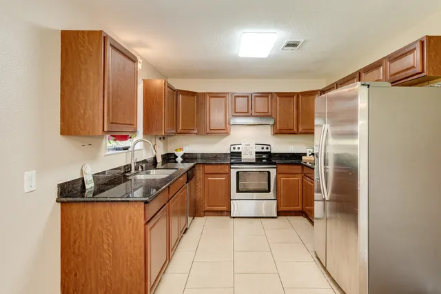 a kitchen with stainless steel appliances granite countertop a sink stove and refrigerator