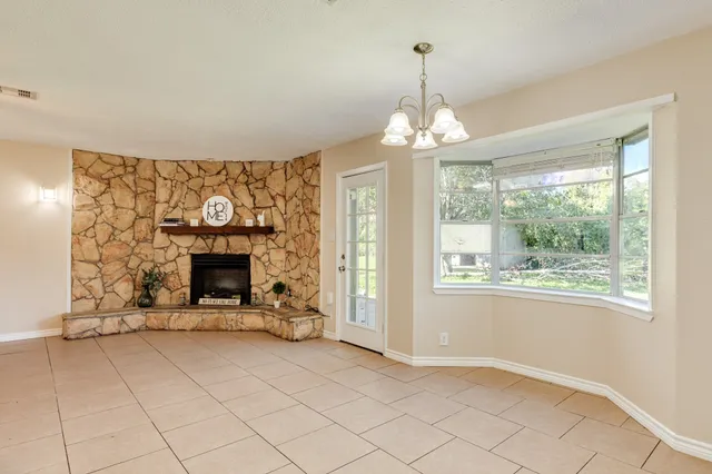 a view of a livingroom with a fireplace a chandelier and windows