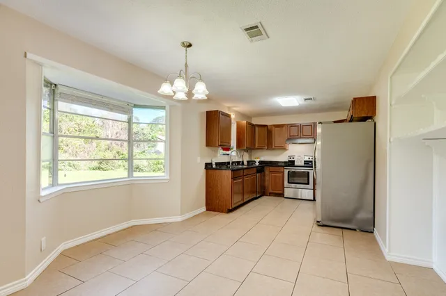 a kitchen with granite countertop a refrigerator and a stove top oven