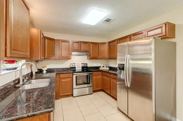 a kitchen with granite countertop stainless steel appliances cabinets a sink and a counter top space