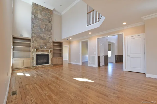 a view of a hallway with wooden floor a fireplace and a kitchen space