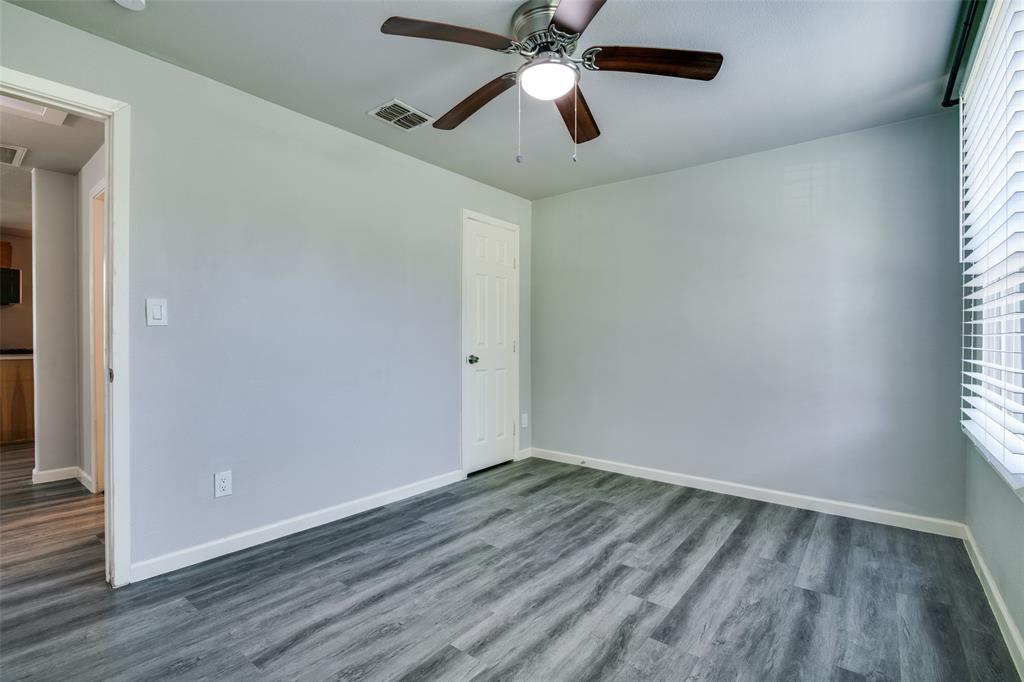 606 West High Street Terrell, TX 75160 - Photo 19 of 28 an empty room with wooden floor ceiling fan and windows