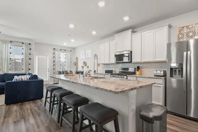 a kitchen with stainless steel appliances granite countertop a stove a sink a microwave a refrigerator and cabinets