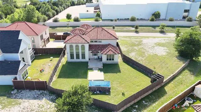 an aerial view of a houses with swimming pool and a yard