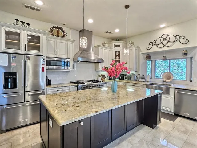 a kitchen with stainless steel appliances granite countertop a kitchen island a stove and a sink