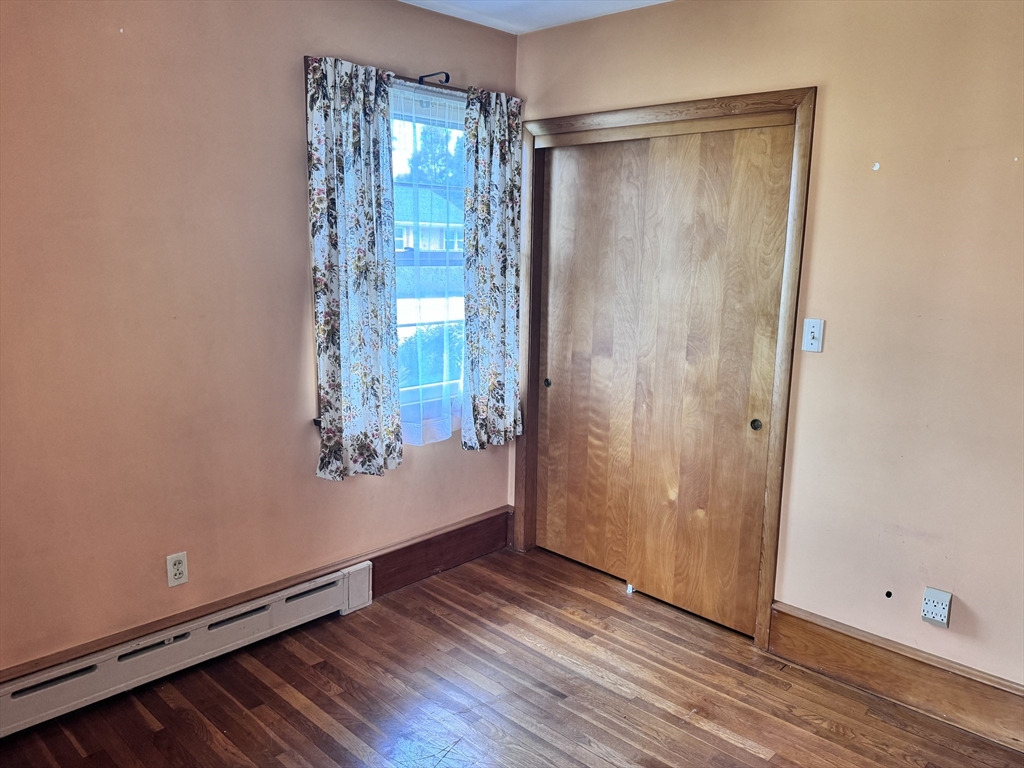 77 Grattan Street Fall River, MA 02721 - Photo 16 of 20 an empty room with wooden floor and windows with curtains