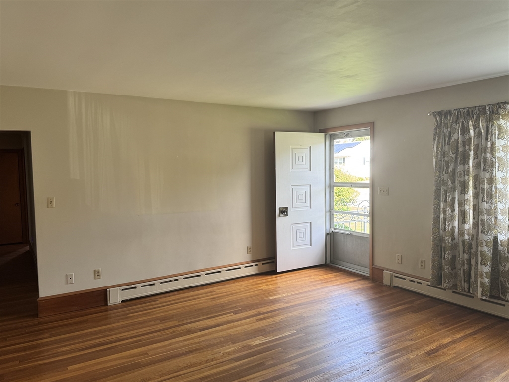 77 Grattan Street Fall River, MA 02721 - Photo 8 of 20 an empty room with wooden floor and windows with curtains