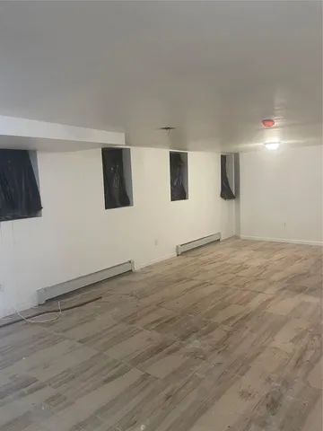 a view of an empty room with wooden floor and windows