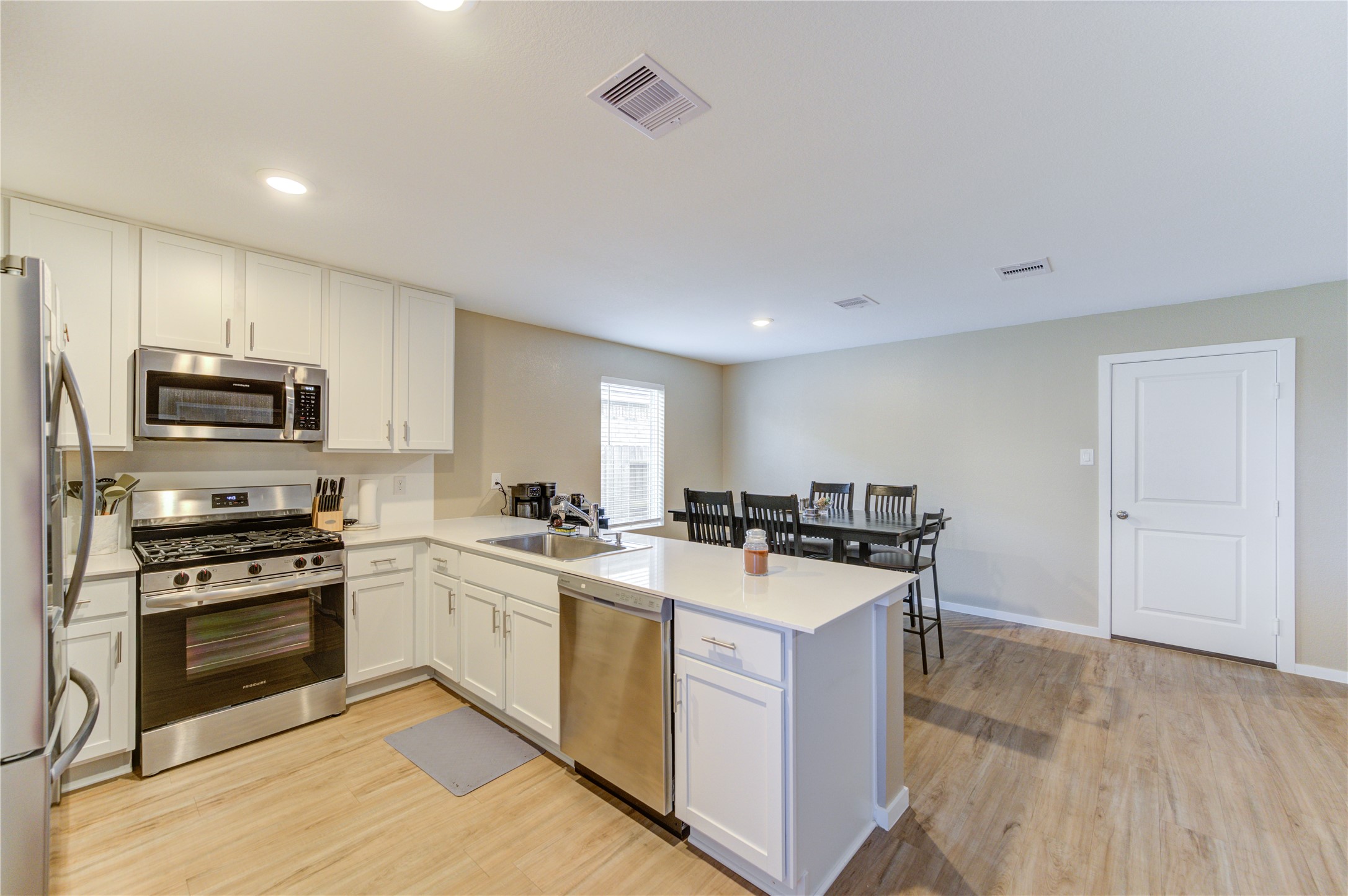 1111 Rustic Willow Drive Beasley, TX 77417 - Photo 15 of 42 This kitchen features modern stainless steel appliances, white cabinetry, and a spacious island with seating. The open layout connects to a dining area with vinyl plank flooring and ample natural light.