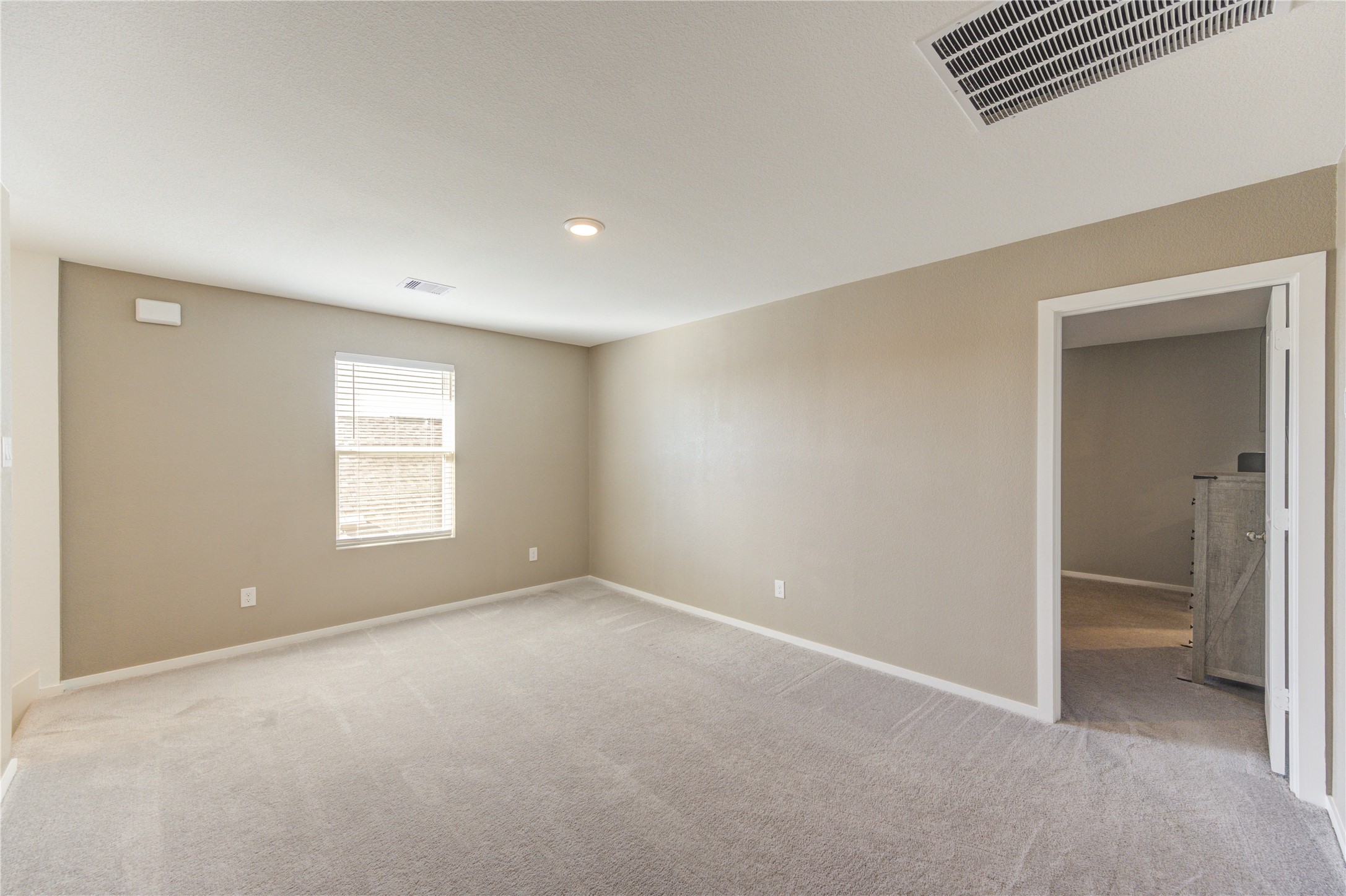 1111 Rustic Willow Drive Beasley, TX 77417 - Photo 19 of 42 This photo shows a spacious, carpeted room with neutral walls and a ceiling light. There's a window allowing natural light, and an open doorway leading to another room, ideal for a cozy living space or bedroom.