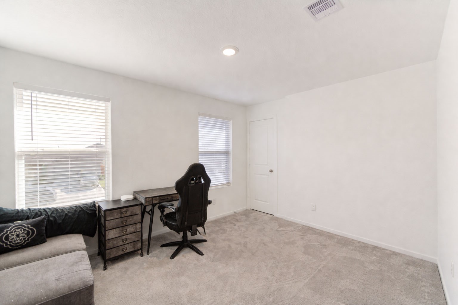 1111 Rustic Willow Drive Beasley, TX 77417 - Photo 22 of 42 Bright room with carpeted flooring, featuring two windows for natural light. Includes a compact desk with a chair and a cozy sofa, ideal for a home office or study area.