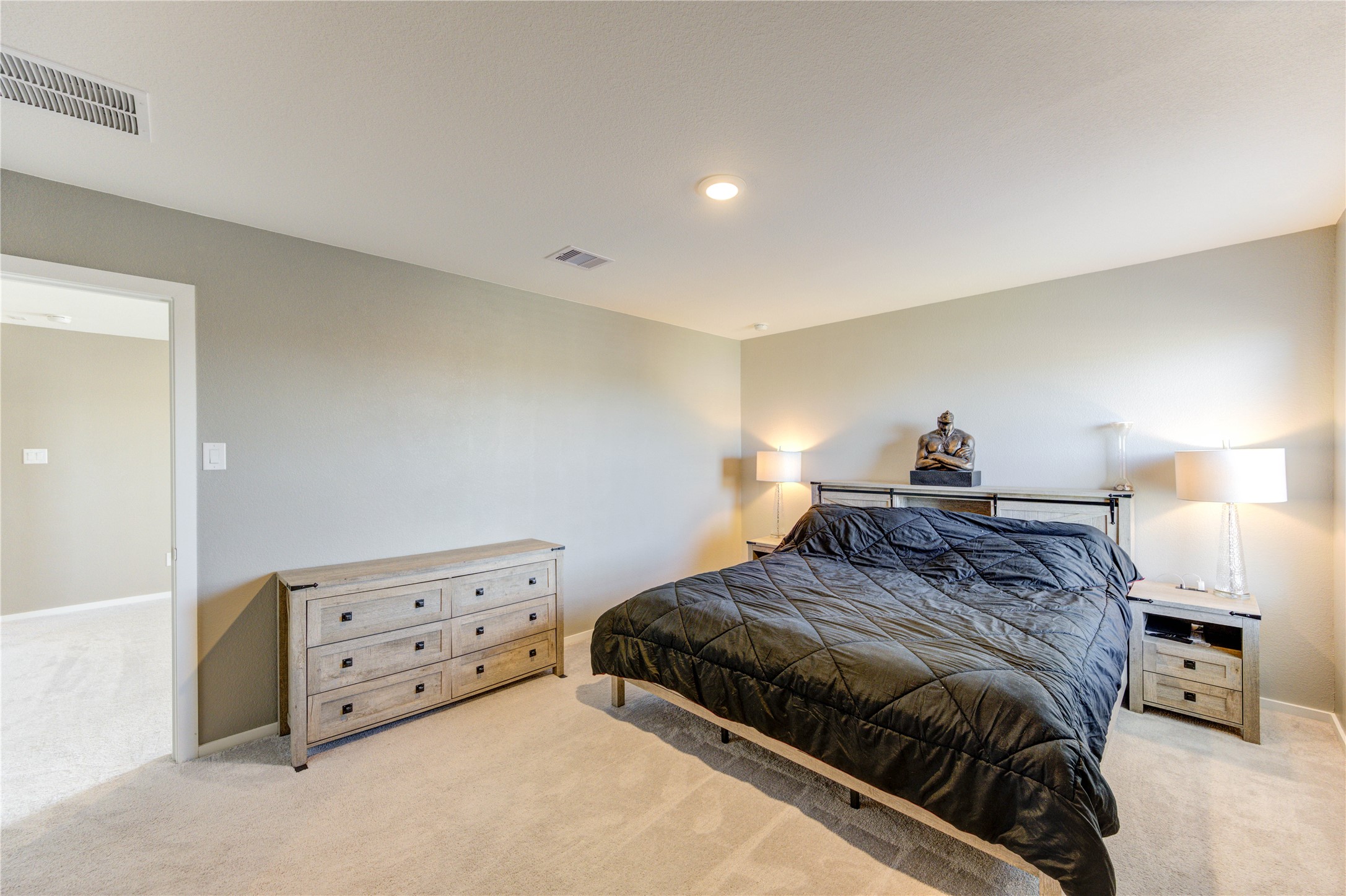1111 Rustic Willow Drive Beasley, TX 77417 - Photo 29 of 42 This is a spacious, well-lit bedroom featuring neutral walls, a cozy carpet, and ample space for furniture. It includes a large bed, a chest of drawers, and bedside tables with modern lamps, giving it a comfortable and inviting feel.