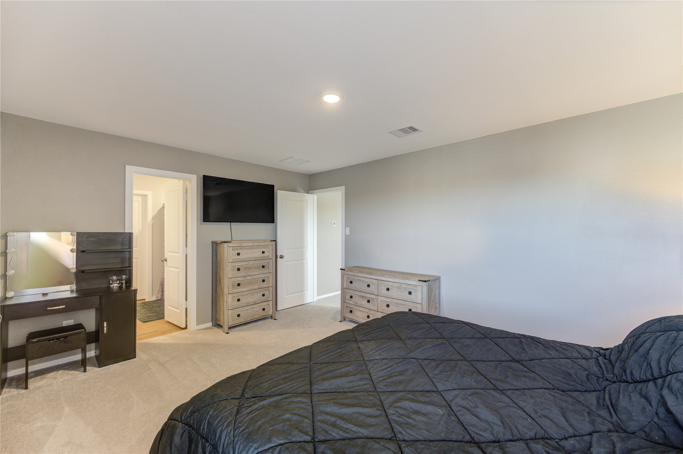 1111 Rustic Willow Drive Beasley, TX 77417 - Photo 30 of 42 This bedroom features a cozy atmosphere with neutral walls, carpeted flooring, and ample natural light. It includes a dresser, a wall-mounted TV, and a vanity. There's an en suite bathroom and a spacious closet for convenience.