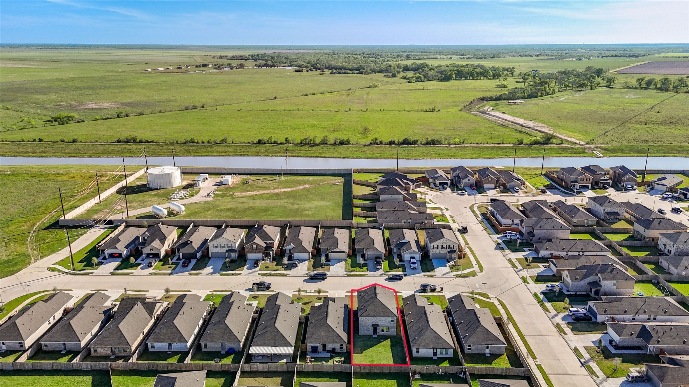 1111 Rustic Willow Drive Beasley, TX 77417 - Photo 37 of 42 This aerial photo shows a suburban home highlighted in a quiet neighborhood. It's situated near open green fields and a canal, offering a semi-rural feel with easy access to surrounding areas. The area appears well-maintained and residential.