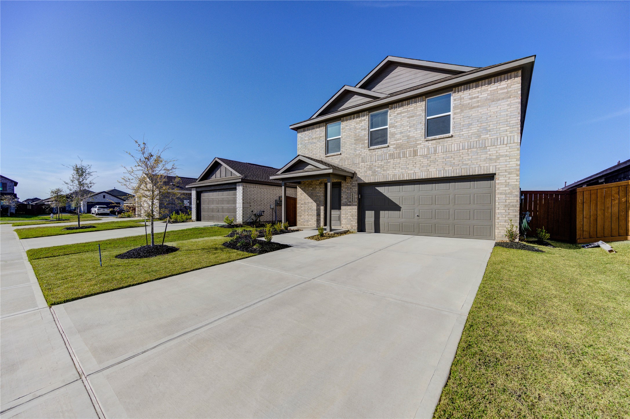 1111 Rustic Willow Drive Beasley, TX 77417 - Photo 4 of 42 This photo features a modern two-story brick home with a two-car garage and a well-maintained front yard. It's situated in a tidy, suburban neighborhood with sidewalks and young trees lining the street.