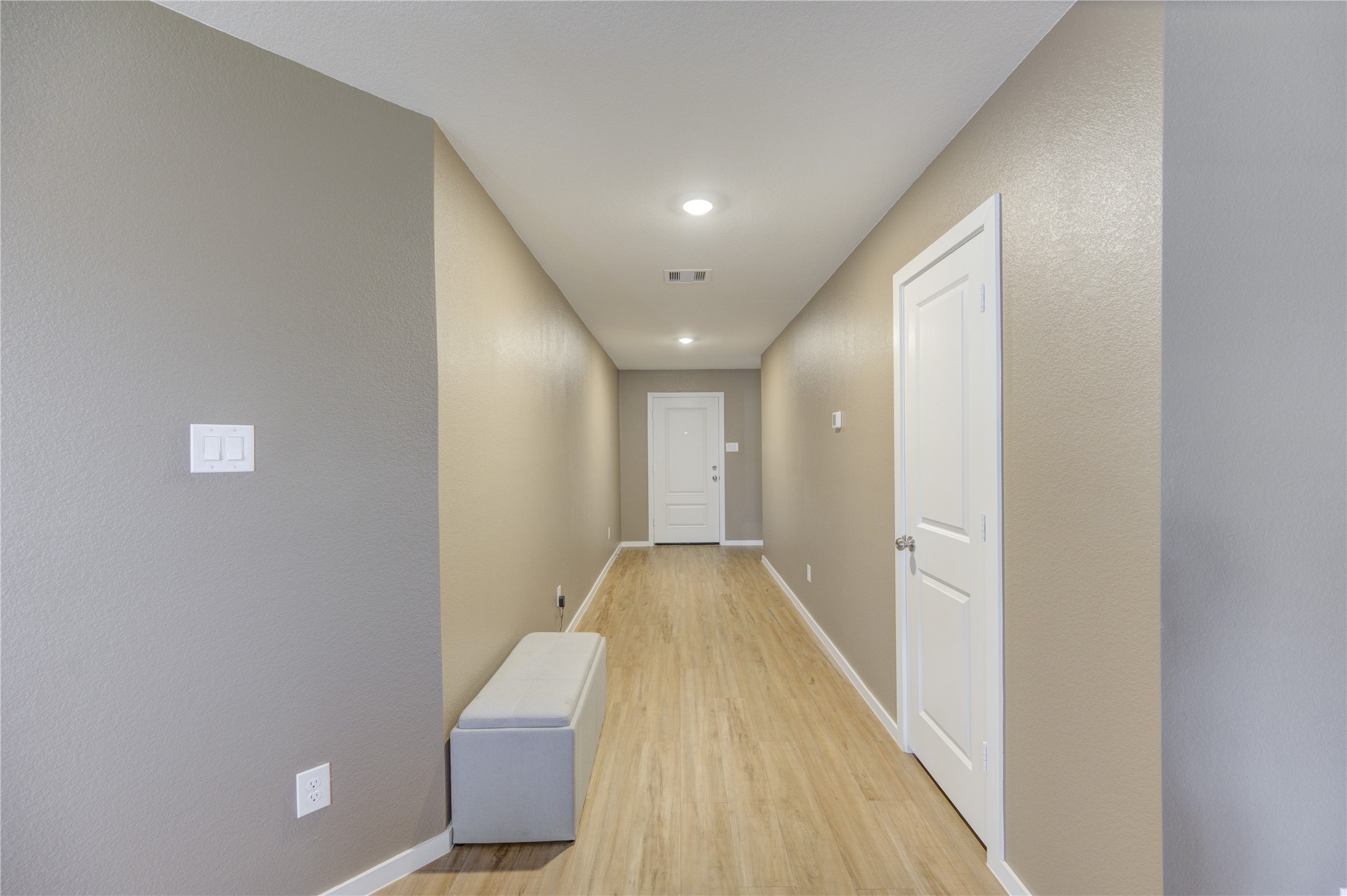 1111 Rustic Willow Drive Beasley, TX 77417 - Photo 5 of 42 This photo shows a well-lit, narrow hallway with light vinyl plank flooring and neutral walls. It features recessed lighting, a white interior door, and a small bench, offering a clean and modern entryway feel.