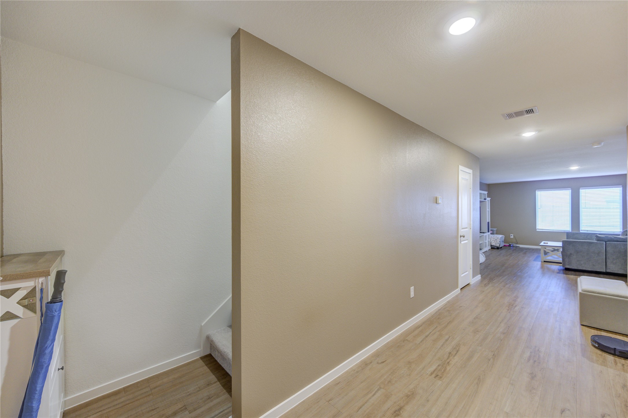 1111 Rustic Willow Drive Beasley, TX 77417 - Photo 6 of 42 This photo shows a modern, open-concept living area with vinyl plank flooring, neutral walls, and recessed lighting. A staircase is visible, leading to another level, and large windows provide natural light to the spacious room.