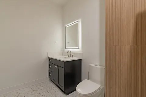 a bathroom with a granite countertop sink toilet a mirror and shower