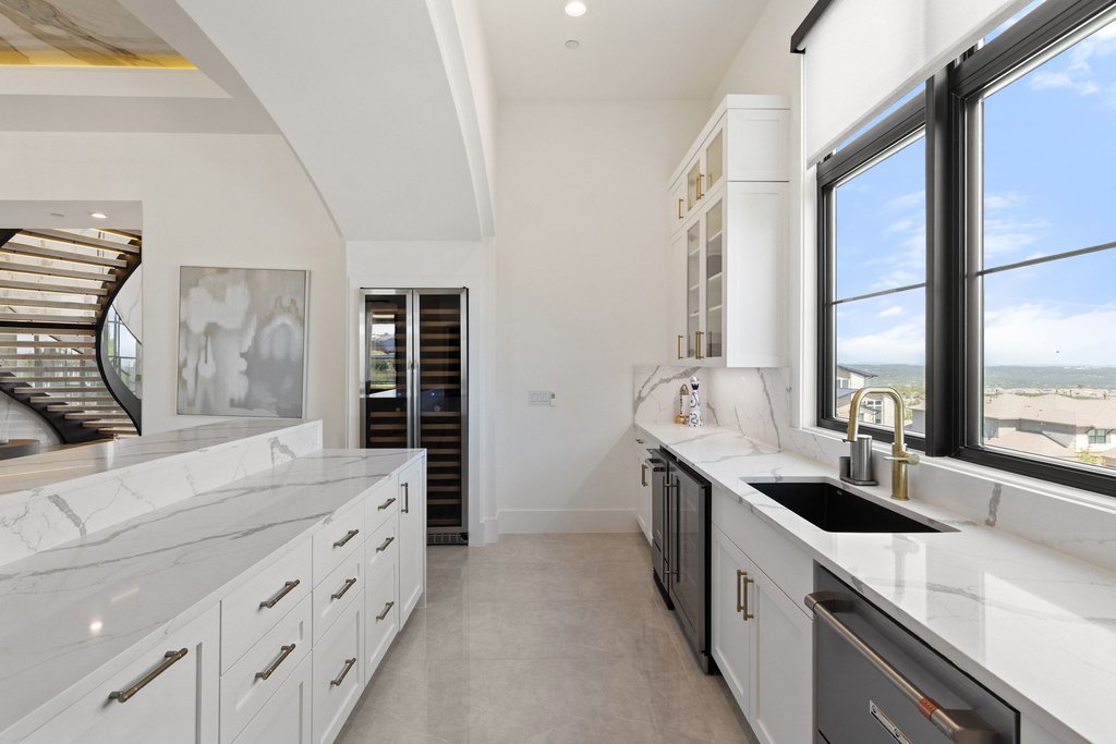 7117 Davenport Divide Road Austin, TX 78738 - Photo 29 of 40 A refined wet bar with sleek cabinetry, a dedicated wine refrigerator, and a scenic window view.