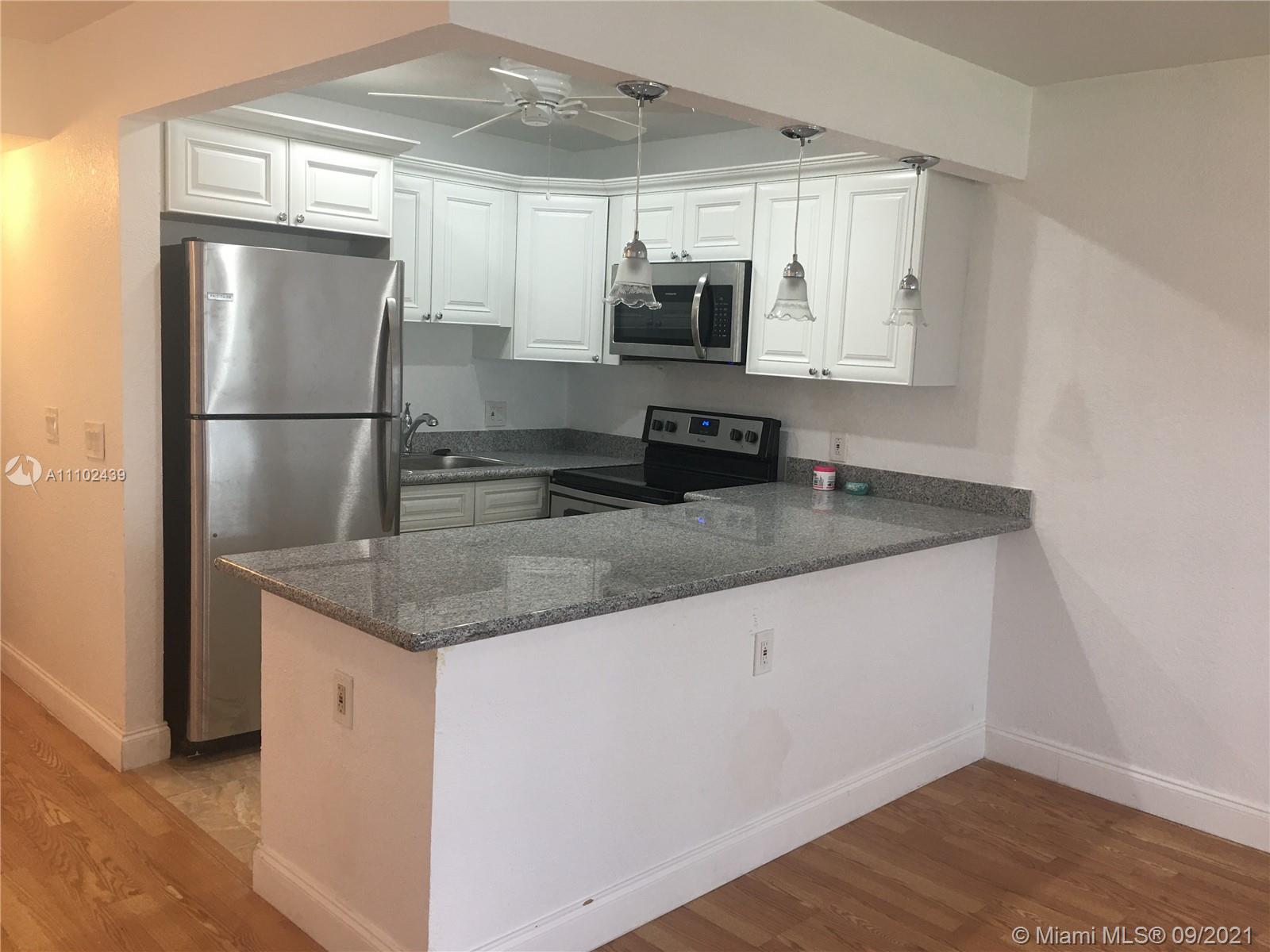 331 Farnham P, Unit 331 Deerfield Beach, FL 33442 - Photo 1 of 11 a kitchen with stainless steel appliances granite countertop a refrigerator a microwave a sink and white cabinets
