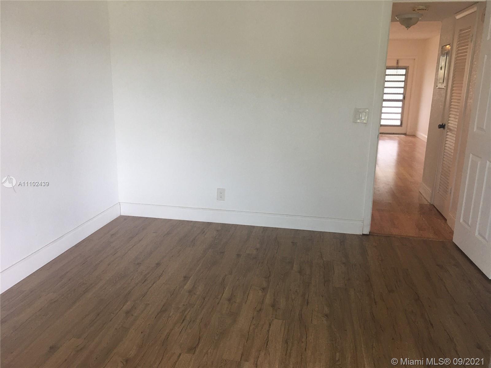 331 Farnham P, Unit 331 Deerfield Beach, FL 33442 - Photo 9 of 11 an empty room with wooden floor and windows