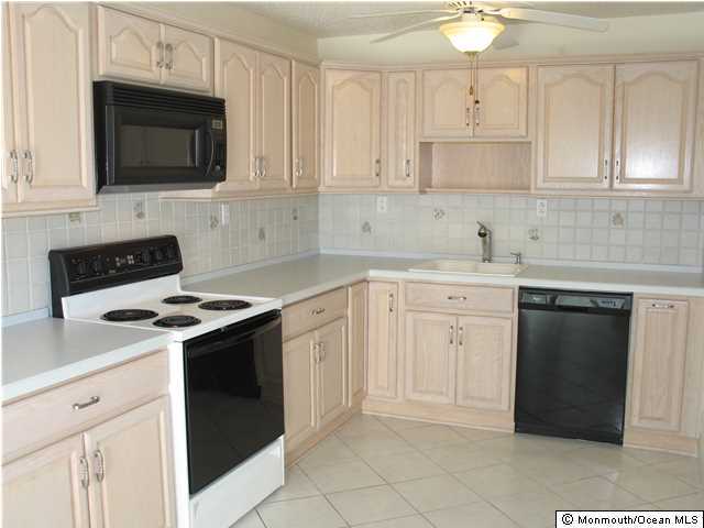 95 Halls Croft Road, Unit A Freehold, NJ 07728 - Photo 1 of 15 a kitchen with granite countertop white cabinets and black appliances