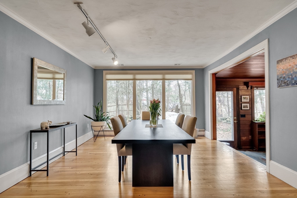 215 Mossman Road Sudbury, MA 01776 - Photo 10 of 30 a dining room with wooden floor a chandelier a glass table and windows