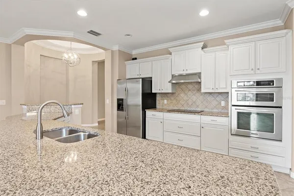 a kitchen with stainless steel appliances granite countertop a sink a refrigerator and a granite counter tops