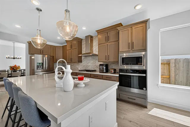 a kitchen with stainless steel appliances granite countertop a stove a refrigerator a kitchen island a dining table and chairs with wooden floor