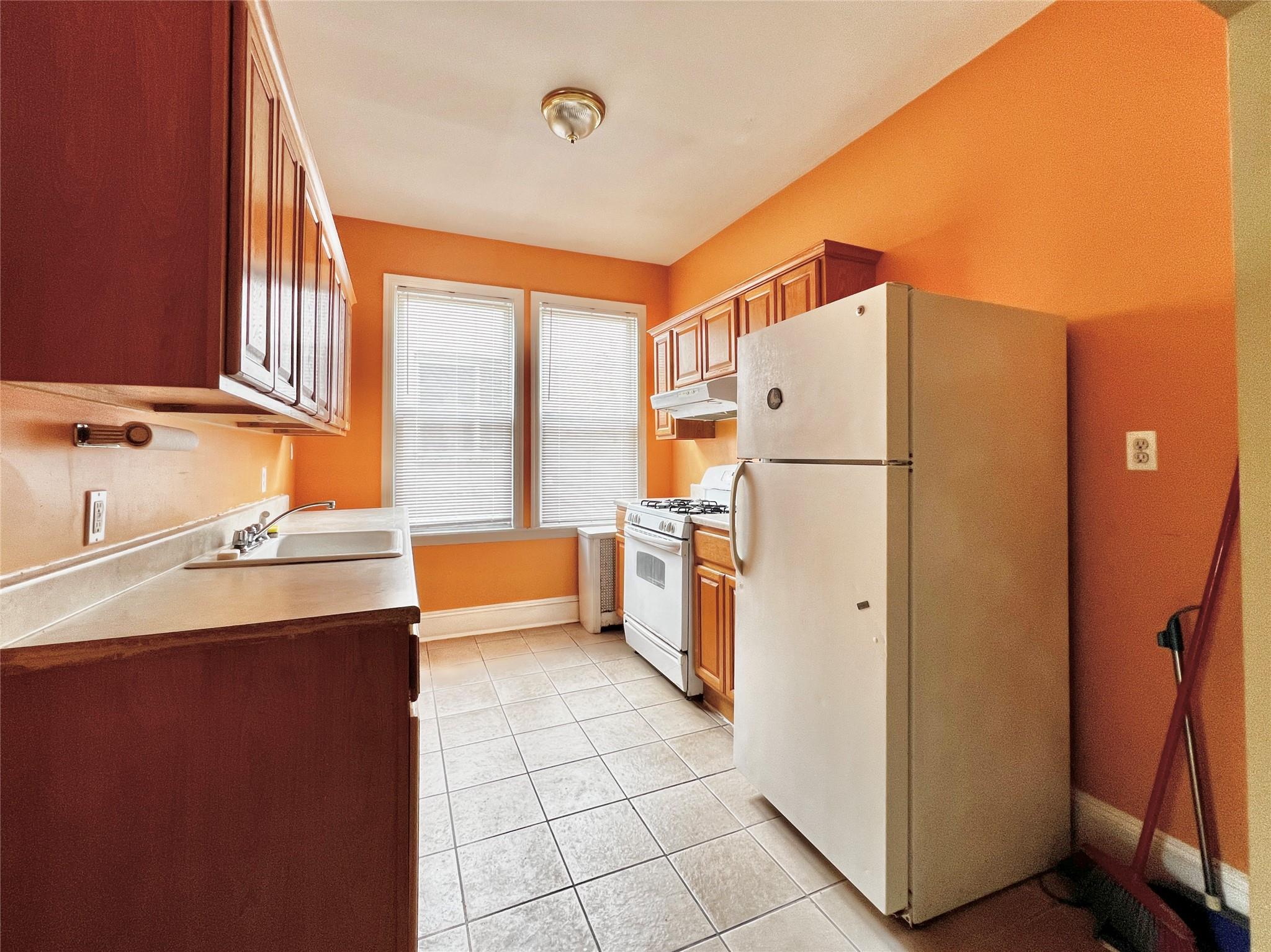 6700 49th Avenue Queens, NY 11377 - Photo 2 of 11 a kitchen with a refrigerator a sink and dishwasher with a dining table next to a window