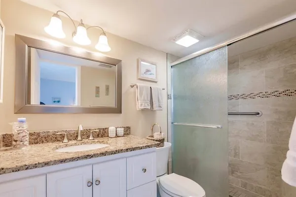 a bathroom with a granite countertop sink toilet and shower