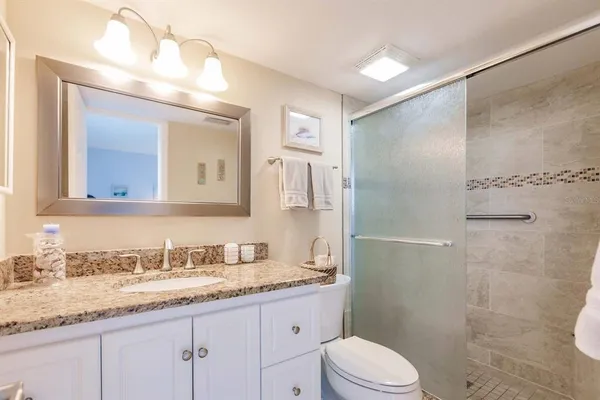 a bathroom with a granite countertop sink toilet a large mirror a shower and vanity