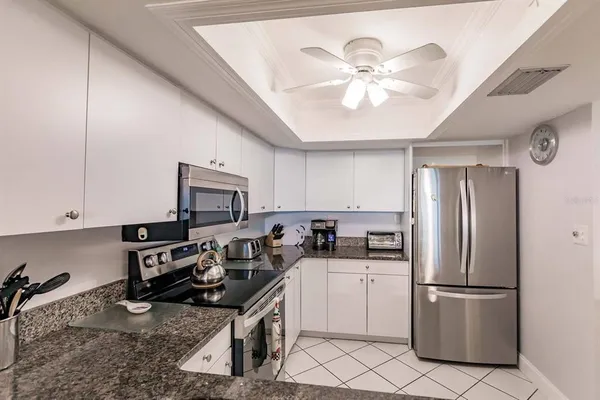 a kitchen with a refrigerator a stove cabinets and living room view
