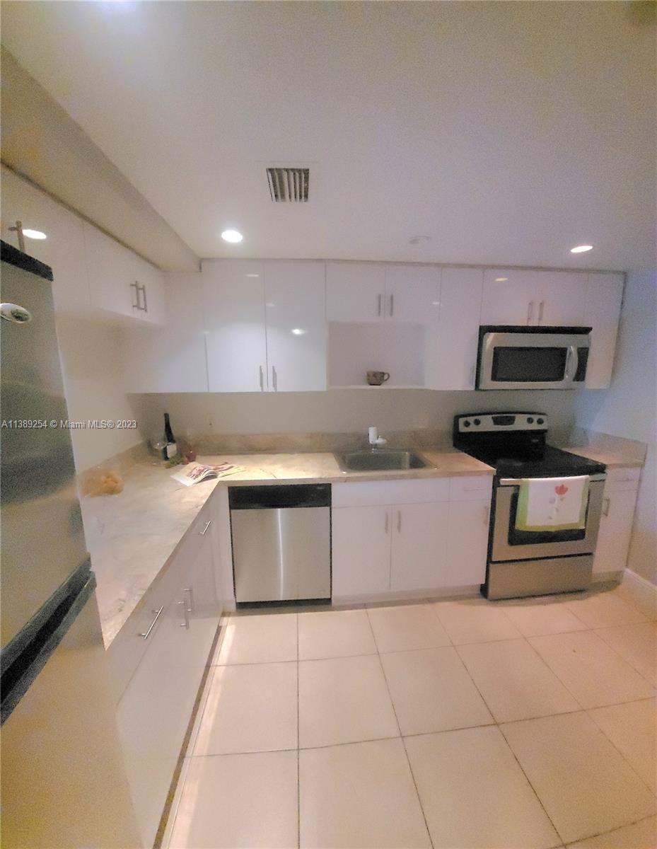 3490 Foxcroft Road, Unit B202 Miramar, FL 33025 - Photo 14 of 29 a large kitchen with a stove a microwave and a refrigerator