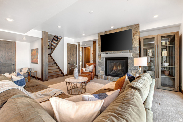 1282 Chimney Rock Road, Unit 344 Heber City, UT 84032 - Photo 29 of 55 Expansive living area featuring a stone-clad fireplace with mantel, built-in display cabinetry, wood-finish doors, and a wood staircase with metal balusters