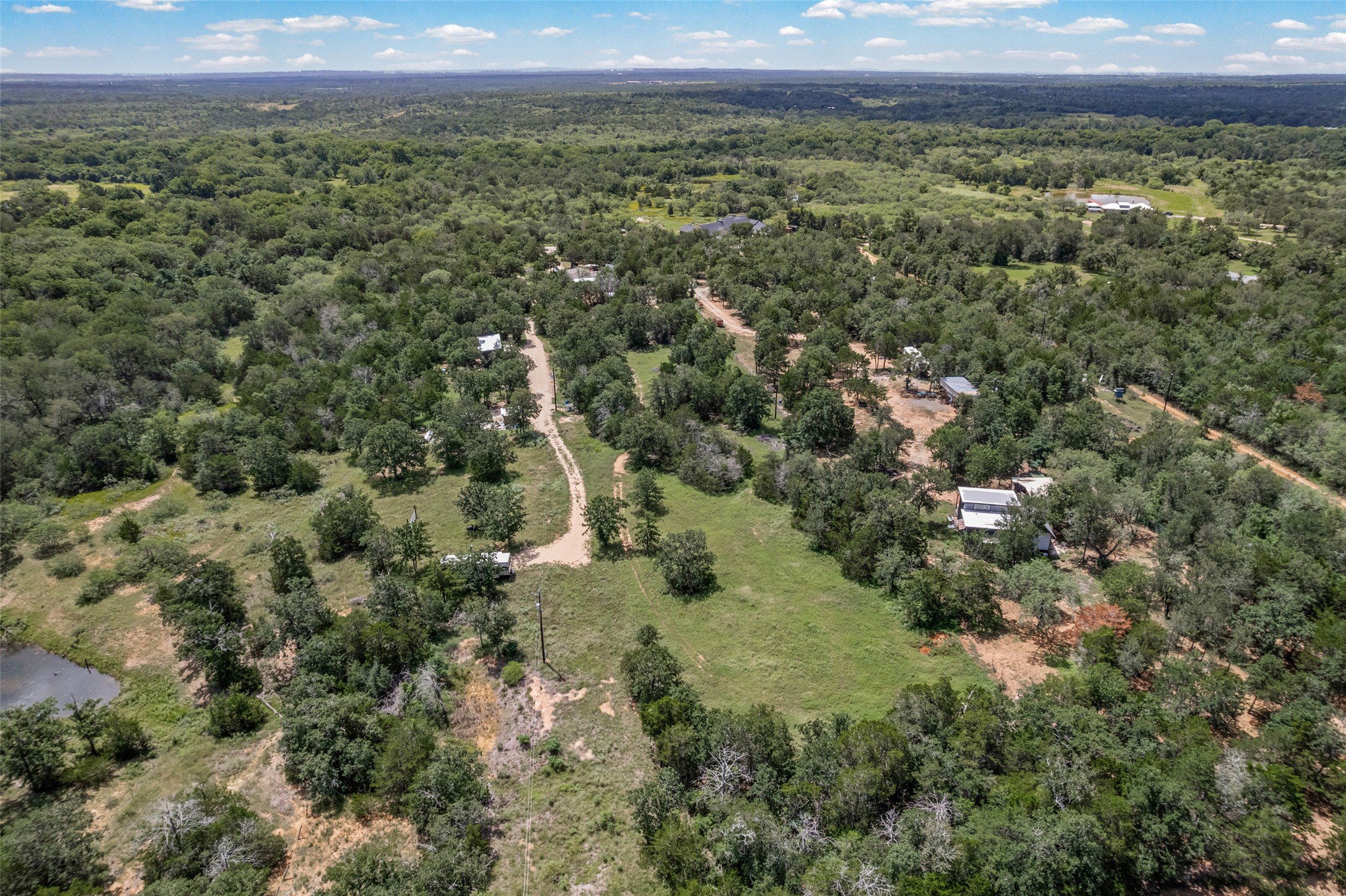 564 Boyd Road Red Rock, TX 78662 - Photo 4 of 25 Vast natural landscape provides a tranquil retreat amidst a canopy of mature trees and distant structures.