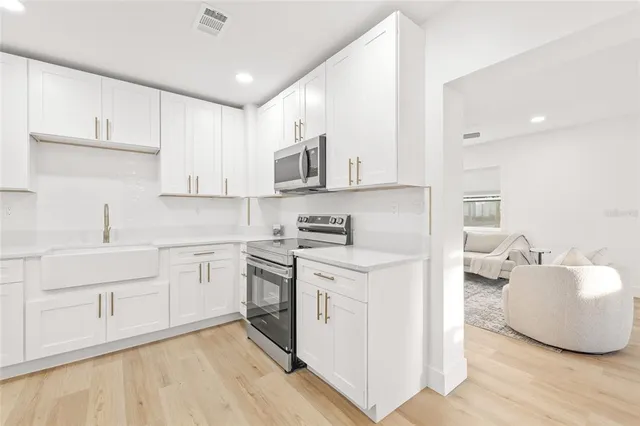 a kitchen with stainless steel appliances granite countertop a sink a stove and cabinets