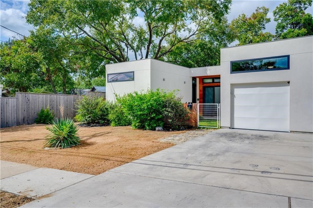 front view of house with potted plants and a large tree