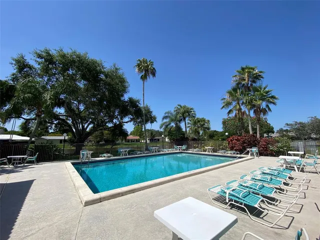 a view of a swimming pool with a bench and trees around