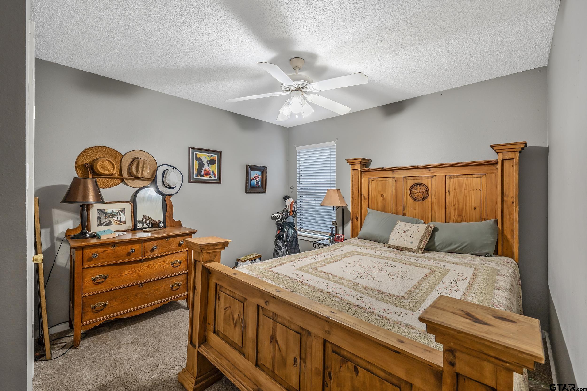 201 Elmwood Lane Holly Lake Ranch, TX 75765 - Photo 11 of 34 a bedroom with a bed and a chandelier