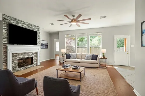 a view of an empty room with wooden floor fireplace and a window
