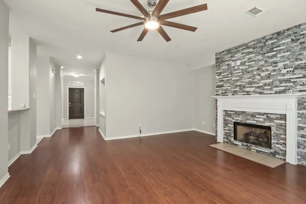 a view of an empty room with wooden floor fireplace and a window