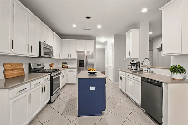 a kitchen with a sink dishwasher a stove and white cabinets